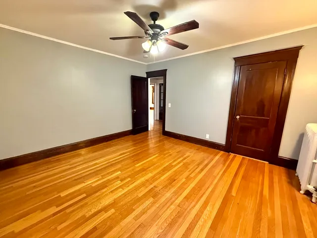 a view of empty room with wooden floor and fan