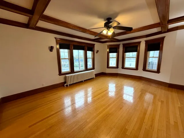 a view of empty room with wooden floor and fan