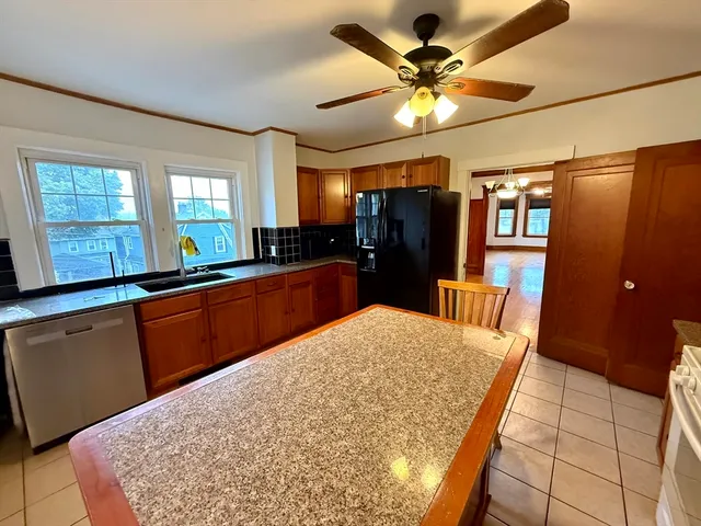 a kitchen with stainless steel appliances kitchen island granite countertop a refrigerator and a sink