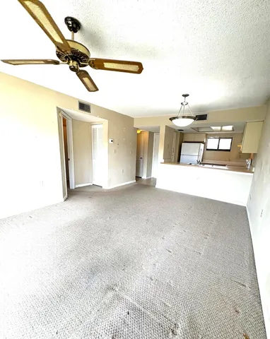 an empty room with windows and ceiling fan