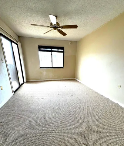an empty room with windows and ceiling fan