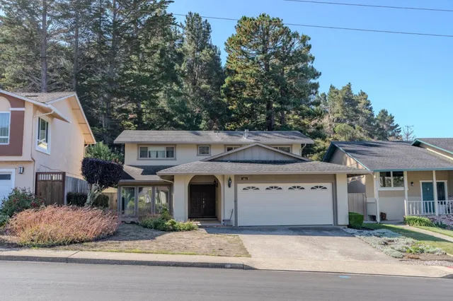 a front view of a house with garden and parking
