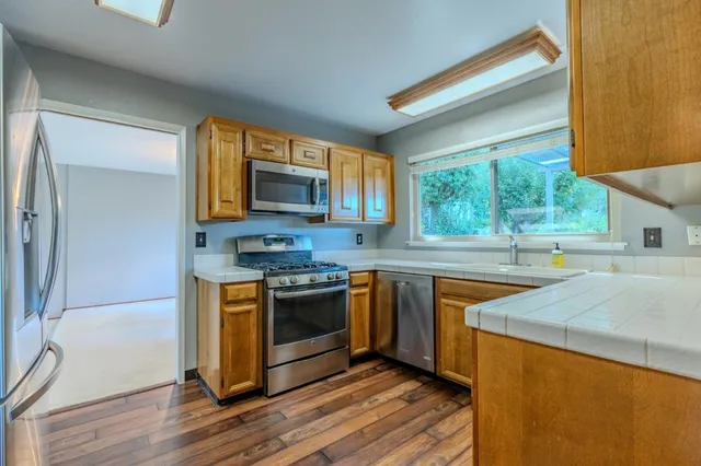 a kitchen with stainless steel appliances granite countertop a stove a sink and a microwave