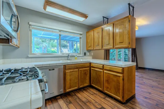 a kitchen with stainless steel appliances granite countertop wooden cabinets a stove a sink and a window