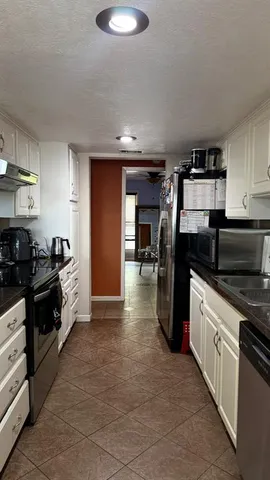 a kitchen with stainless steel appliances granite countertop a refrigerator a stove and a sink