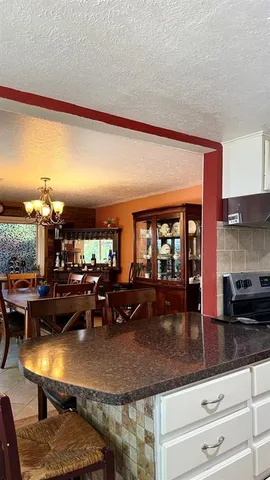 a kitchen with stainless steel appliances granite countertop a stove a sink a refrigerator white cabinets and a refrigerator