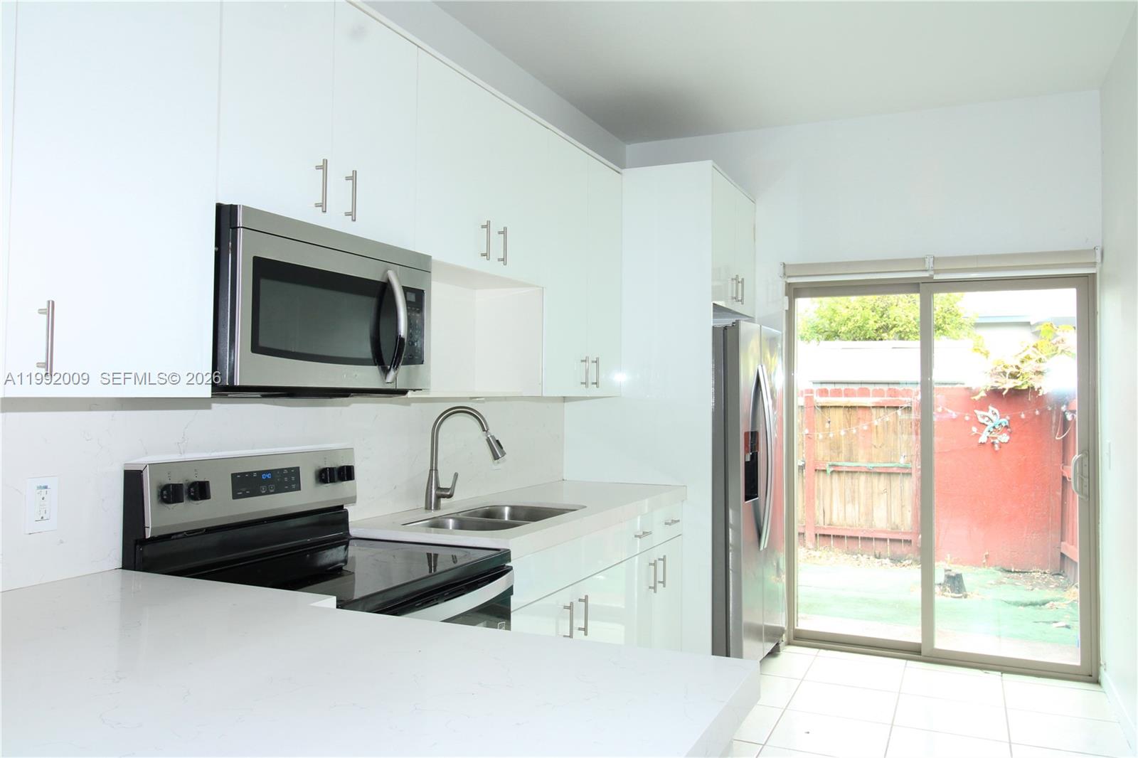 13929 Southwest 282nd Street Homestead, FL 33033 - Photo 10 of 30 a kitchen with granite countertop a stove a sink and a microwave