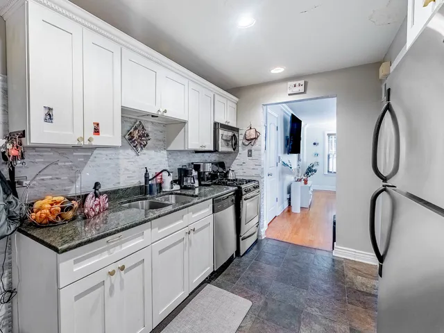 a kitchen with white cabinets and black appliances