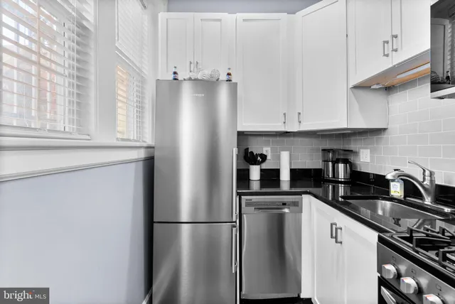 a kitchen with stainless steel appliances granite countertop a refrigerator a stove a sink and white cabinets