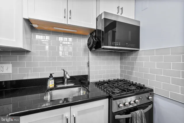 a kitchen with granite countertop a sink stainless steel appliances and cabinets