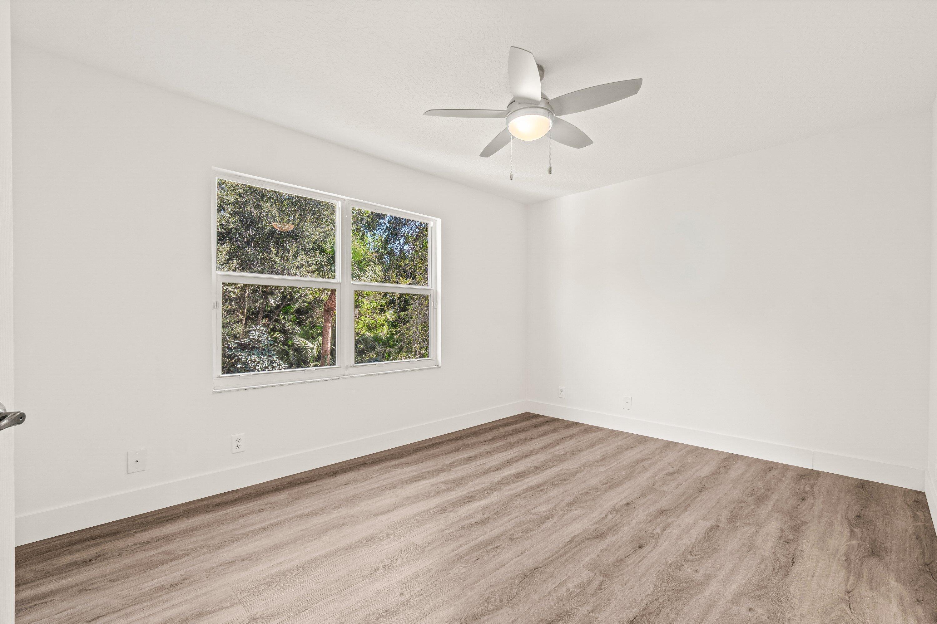 21256 Vía Fiore Boca Raton, FL 33433 - Photo 30 of 42 an empty room with wooden floor chandelier fan and windows