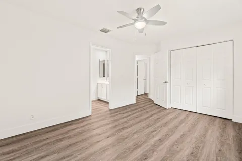 an empty room with wooden floor ceiling fan