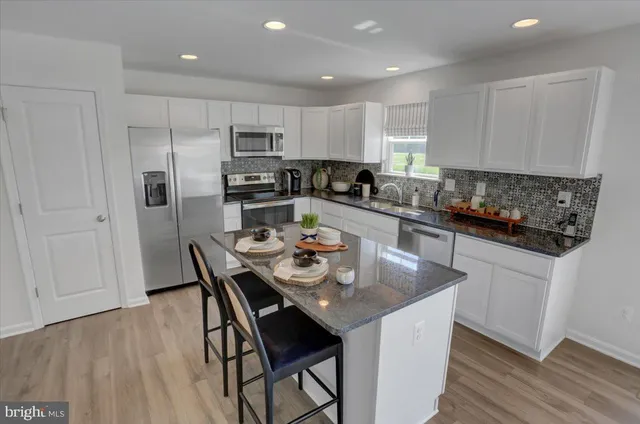 a kitchen with a refrigerator a stove a sink a dining table and chairs