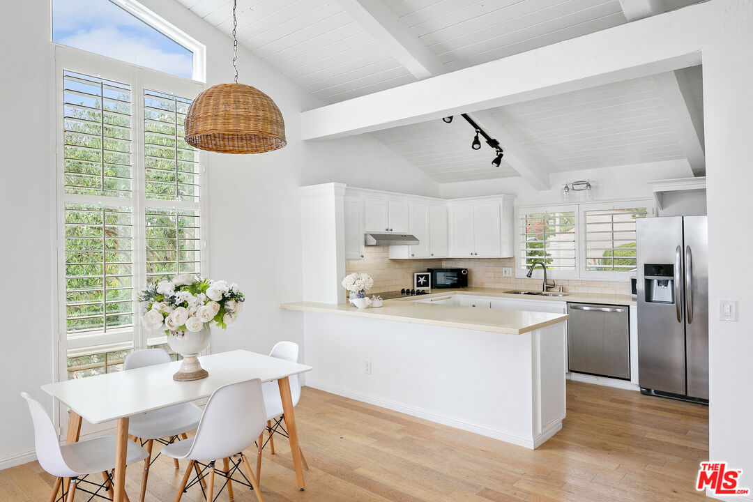 28398 Rey De Copas Lane Malibu, CA 90265 - Photo 6 of 44 a kitchen with stainless steel appliances granite countertop a stove a refrigerator a sink dishwasher a dining table and chairs with wooden floor