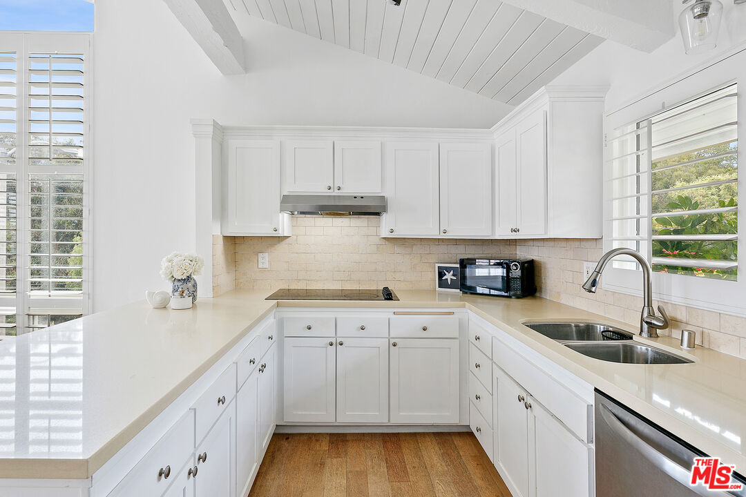 28398 Rey De Copas Lane Malibu, CA 90265 - Photo 8 of 44 a kitchen with granite countertop white cabinets white appliances and sink