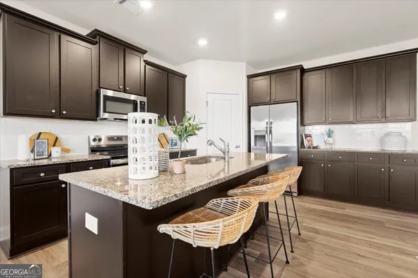 a kitchen with kitchen island granite countertop a sink cabinets and stainless steel appliances