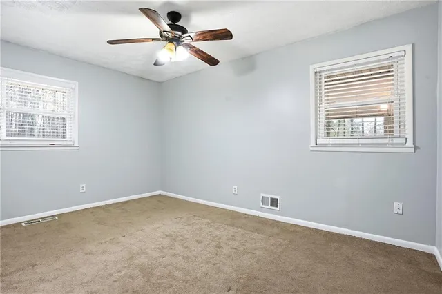 a view of an empty room with a ceiling fan and window
