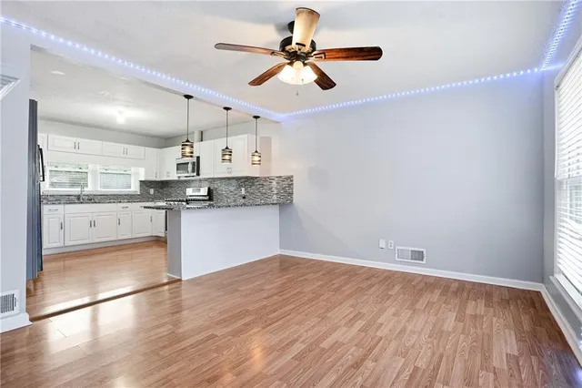 a view of an empty room with wooden floor fireplace and a window
