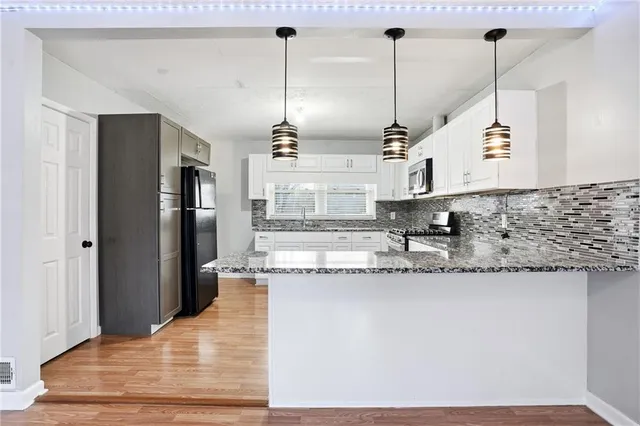 a kitchen with granite countertop white cabinets sink and stainless steel appliances