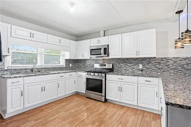 a kitchen with kitchen island granite countertop a stove sink and microwave