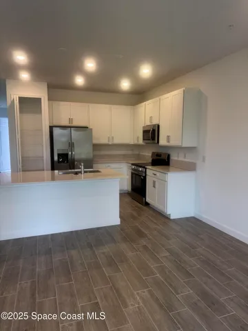 a large kitchen with kitchen island a stove a sink dishwasher and a refrigerator with wooden floor