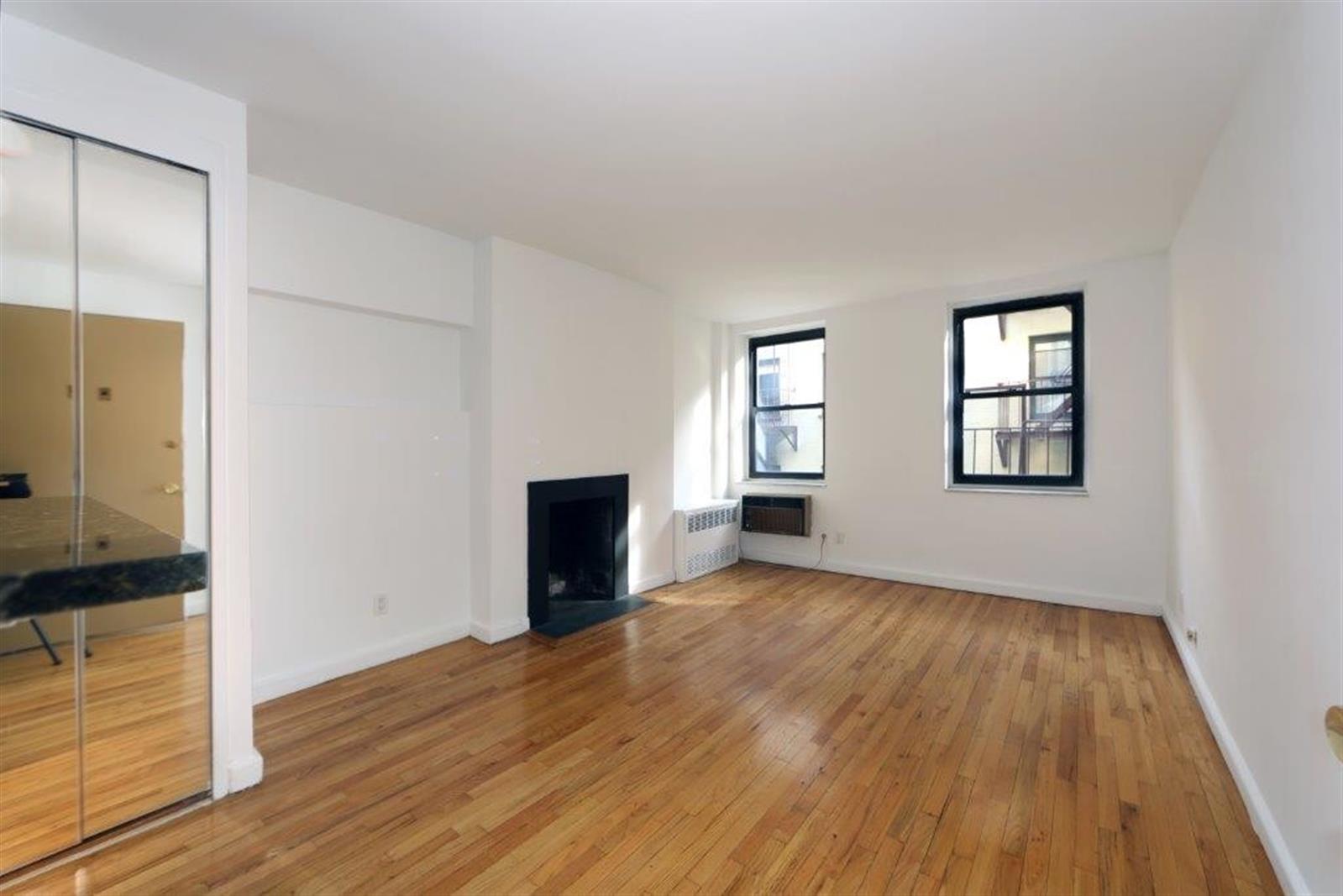 113 Sullivan Street, Unit 20123 Manhattan, NY 10012 - Photo 4 of 15 an empty room with wooden floor and windows