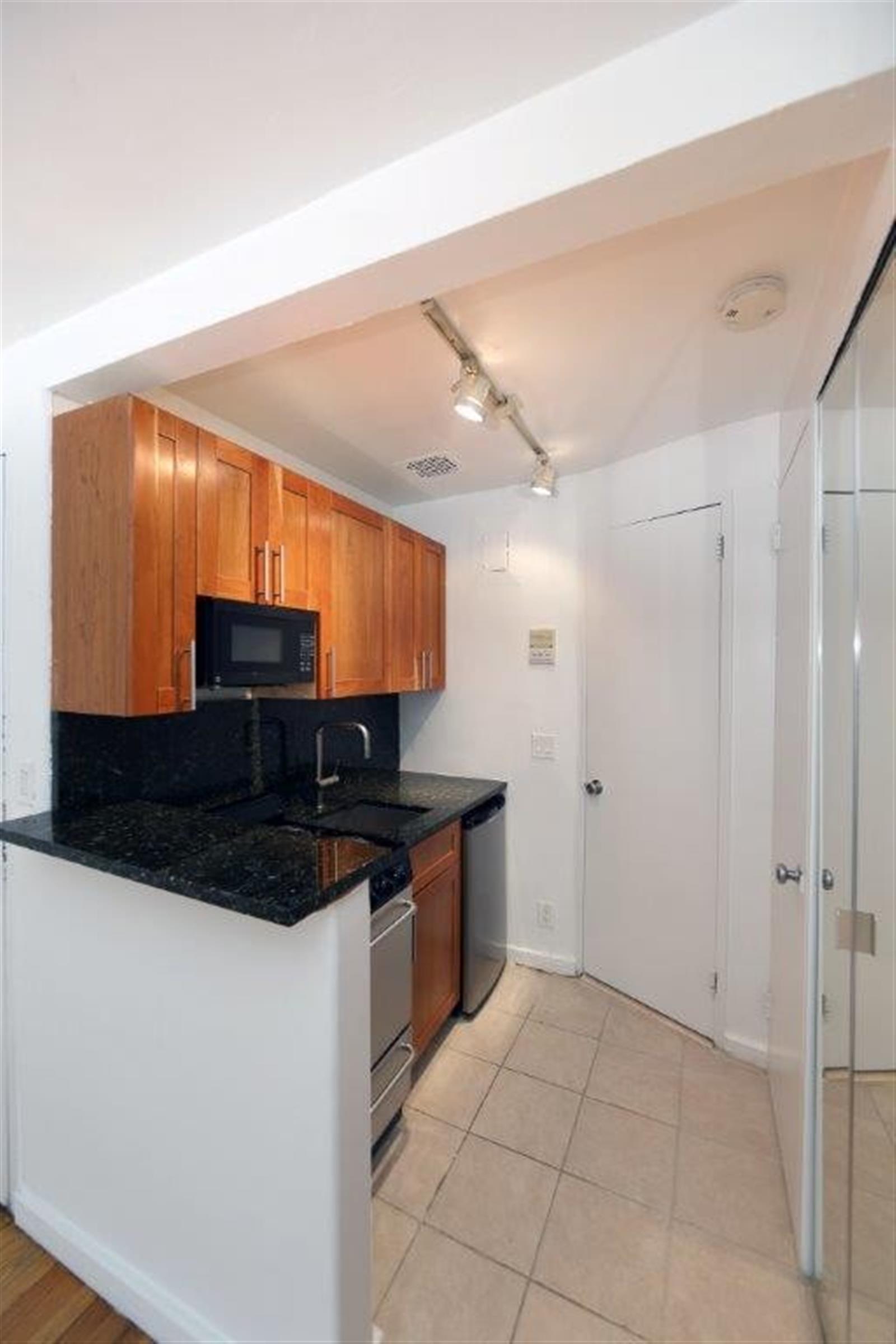 113 Sullivan Street, Unit 20123 Manhattan, NY 10012 - Photo 5 of 15 a kitchen with stainless steel appliances a sink a stove a microwave a refrigerator and cabinets