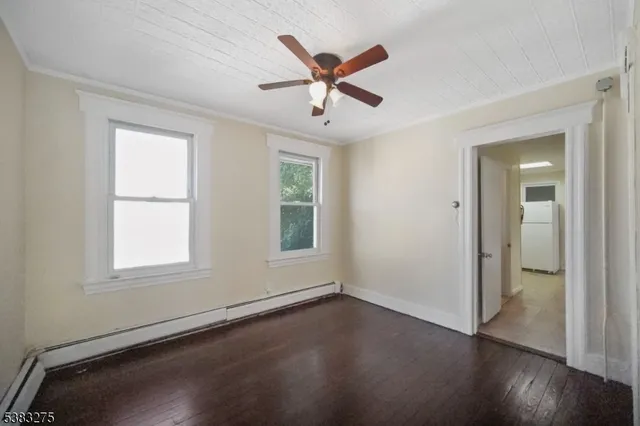 an empty room with wooden floor ceiling fan and windows