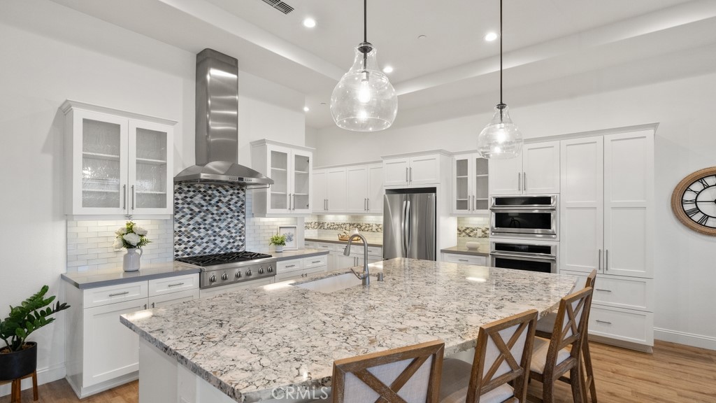 851 Trail View Place Nipomo, CA 93444 - Photo 9 of 47 a kitchen with stainless steel appliances kitchen island granite countertop a stove a refrigerator a sink a dining table and chairs with wooden floor