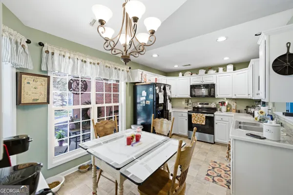 a kitchen with stainless steel appliances kitchen island granite countertop a sink dishwasher a stove a refrigerator oven a dining table and chairs with wooden floor