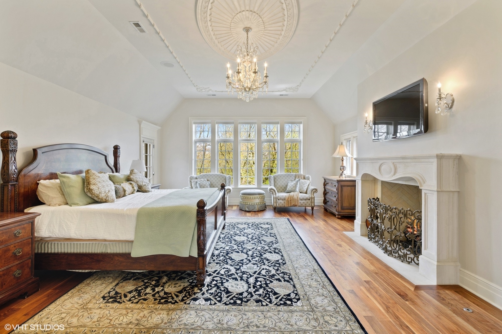 1451 North Green Bay Road Lake Forest, IL 60045 - Photo 27 of 55 a spacious bedroom with a bed a fireplace and a chandelier
