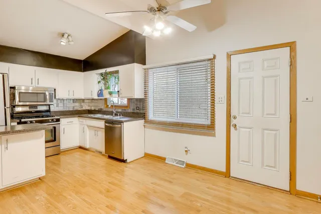 a kitchen with granite countertop a stove a sink dishwasher and a refrigerator with wooden floor
