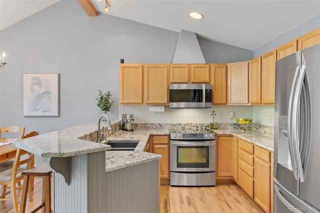 a kitchen with stainless steel appliances a stove a sink a microwave a refrigerator and cabinets