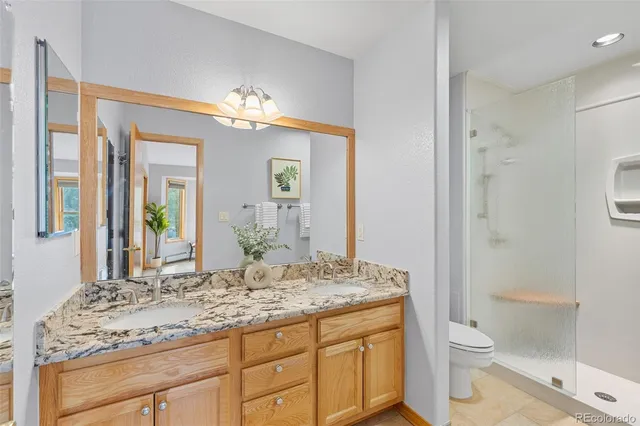 a bathroom with a granite countertop sink toilet a large mirror a shower and a bathtub