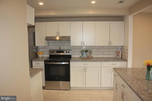 a kitchen with granite countertop a stove sink and cabinets
