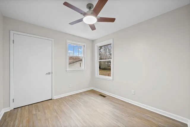 an empty room with wooden floor and ceiling fan