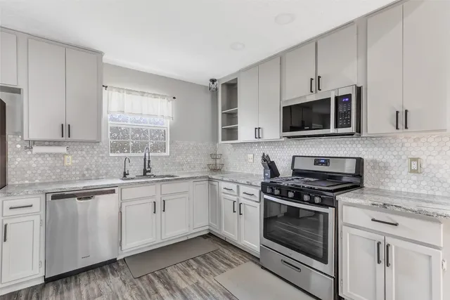a kitchen with cabinets stainless steel appliances a sink and a window