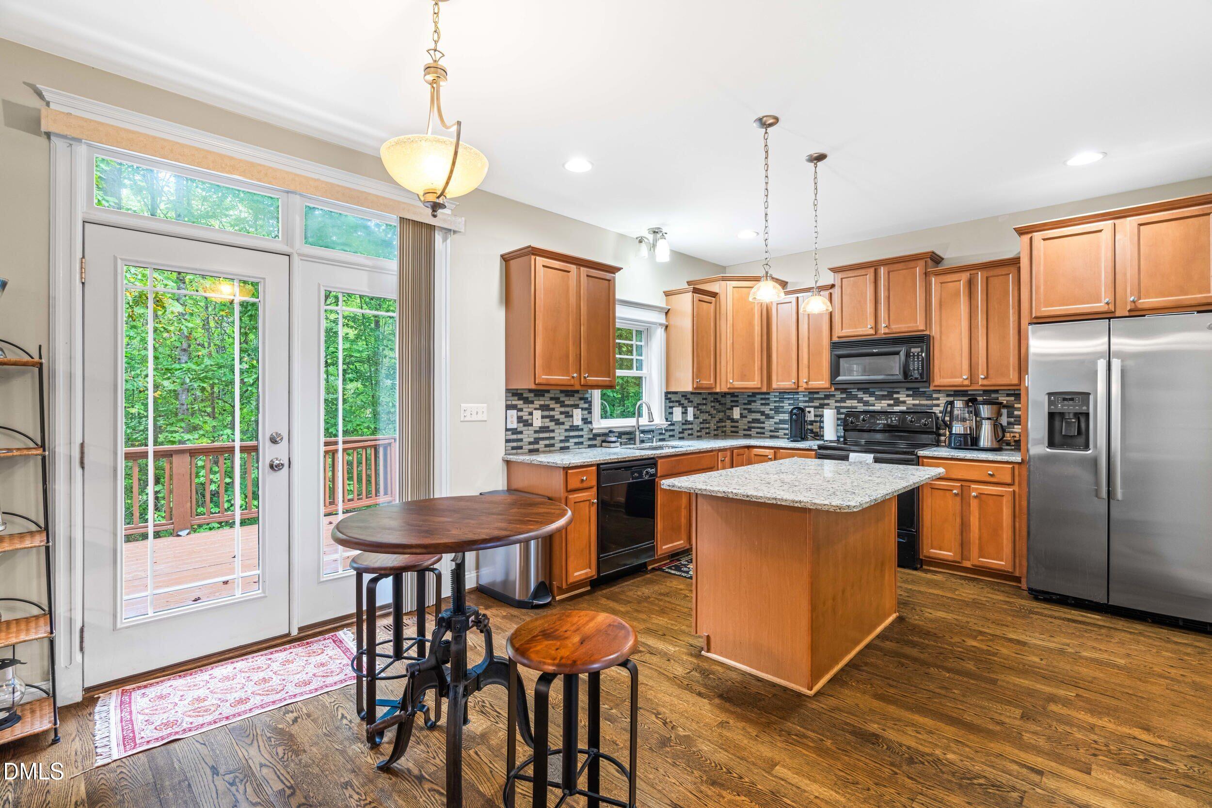 126 Geranium Way Clayton, NC 27527 - Photo 12 of 35 a kitchen with stainless steel appliances granite countertop a stove a refrigerator a kitchen island a table and chairs