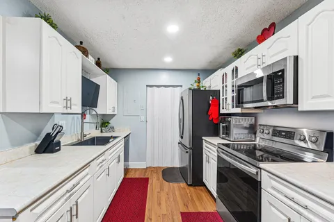 a kitchen with stainless steel appliances a sink a stove a microwave a refrigerator a sink and cabinets