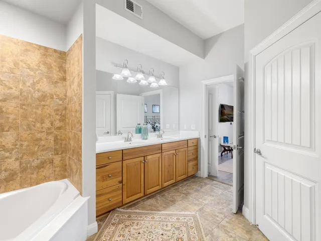 a bathroom with a double vanity sink mirror and bathtub
