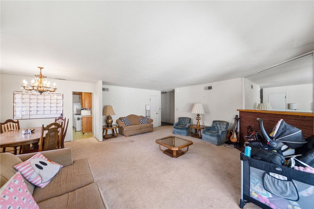 5433 Rochester Street Riverside, CA 92504 - Photo 9 of 29 Wide view of the living and dining areas with carpeted flooring and a brick fireplace.