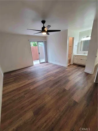 an empty room with wooden floor ceiling fan and windows