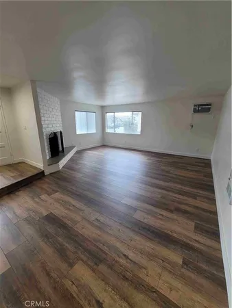 a view of a livingroom with wooden floor and a fireplace