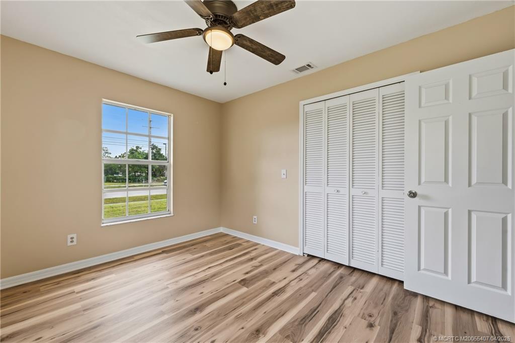 6285 Southeast Highland Avenue Stuart, FL 34997 - Photo 17 of 24 an empty room with wooden floor chandelier fan and windows