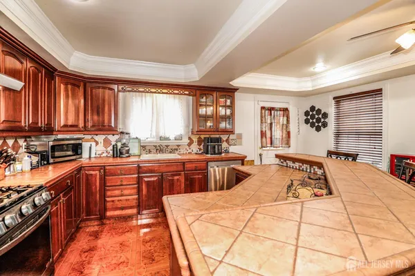 a large kitchen with kitchen island granite countertop a large counter top stainless steel appliances a sink a window and cabinets