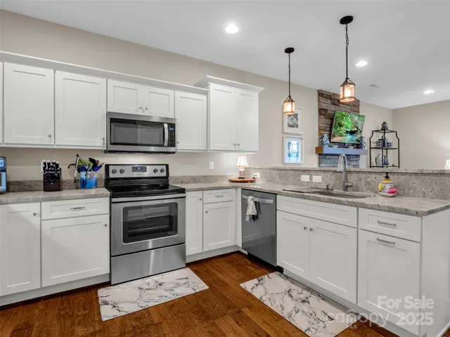 a kitchen with kitchen island granite countertop a sink cabinets and stainless steel appliances