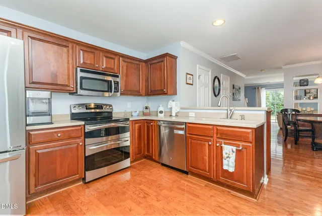 a kitchen with stainless steel appliances granite countertop a stove top oven a sink dishwasher and white cabinets with wooden floor