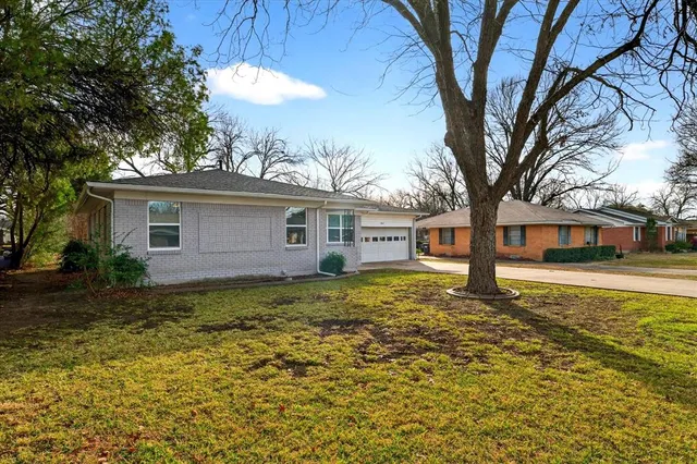 a view of a yard in front of a house with a large tree