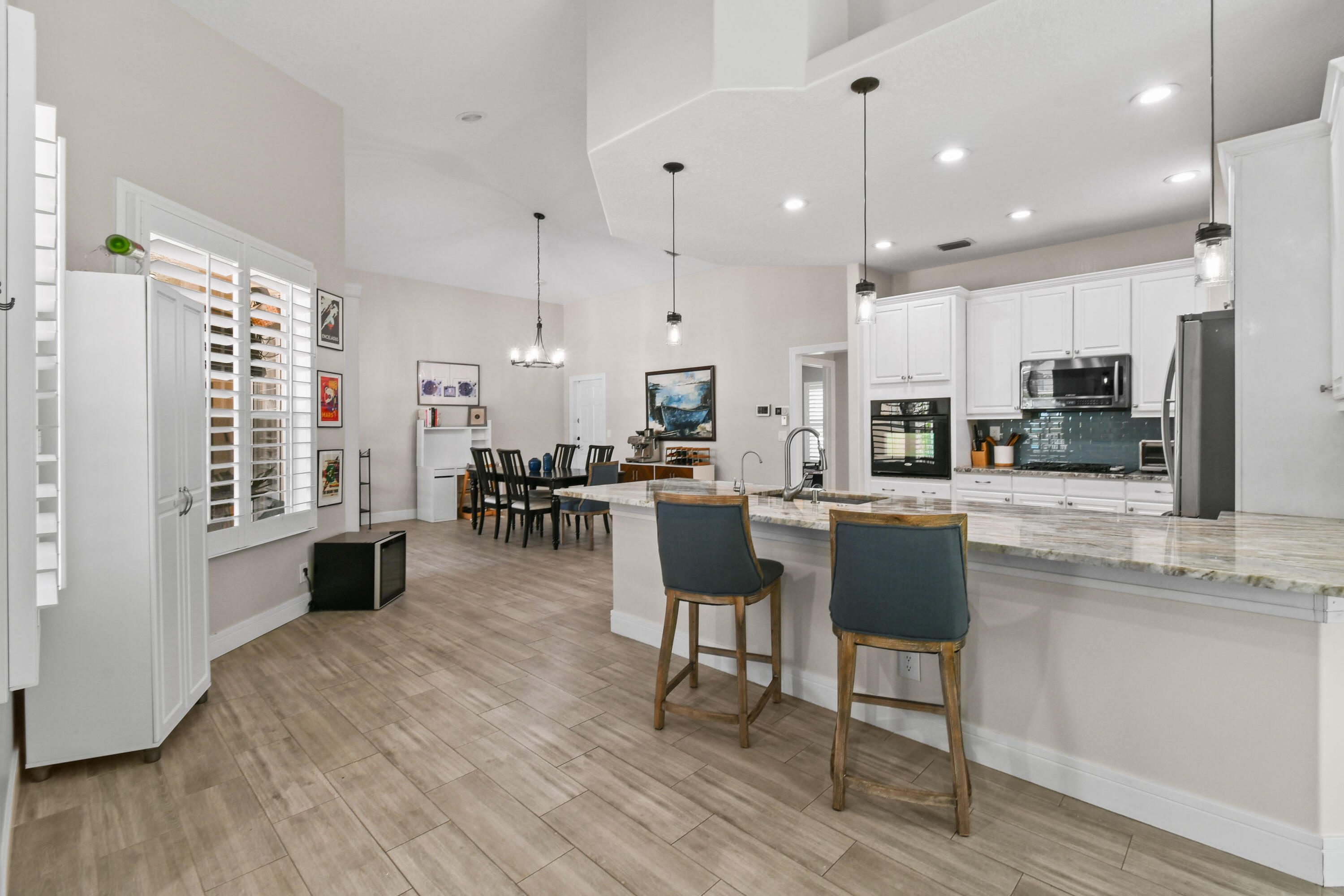 303 Hardwood Point Jupiter, FL 33458 - Photo 20 of 75 a kitchen with stainless steel appliances kitchen island granite countertop a table chairs refrigerator and sink