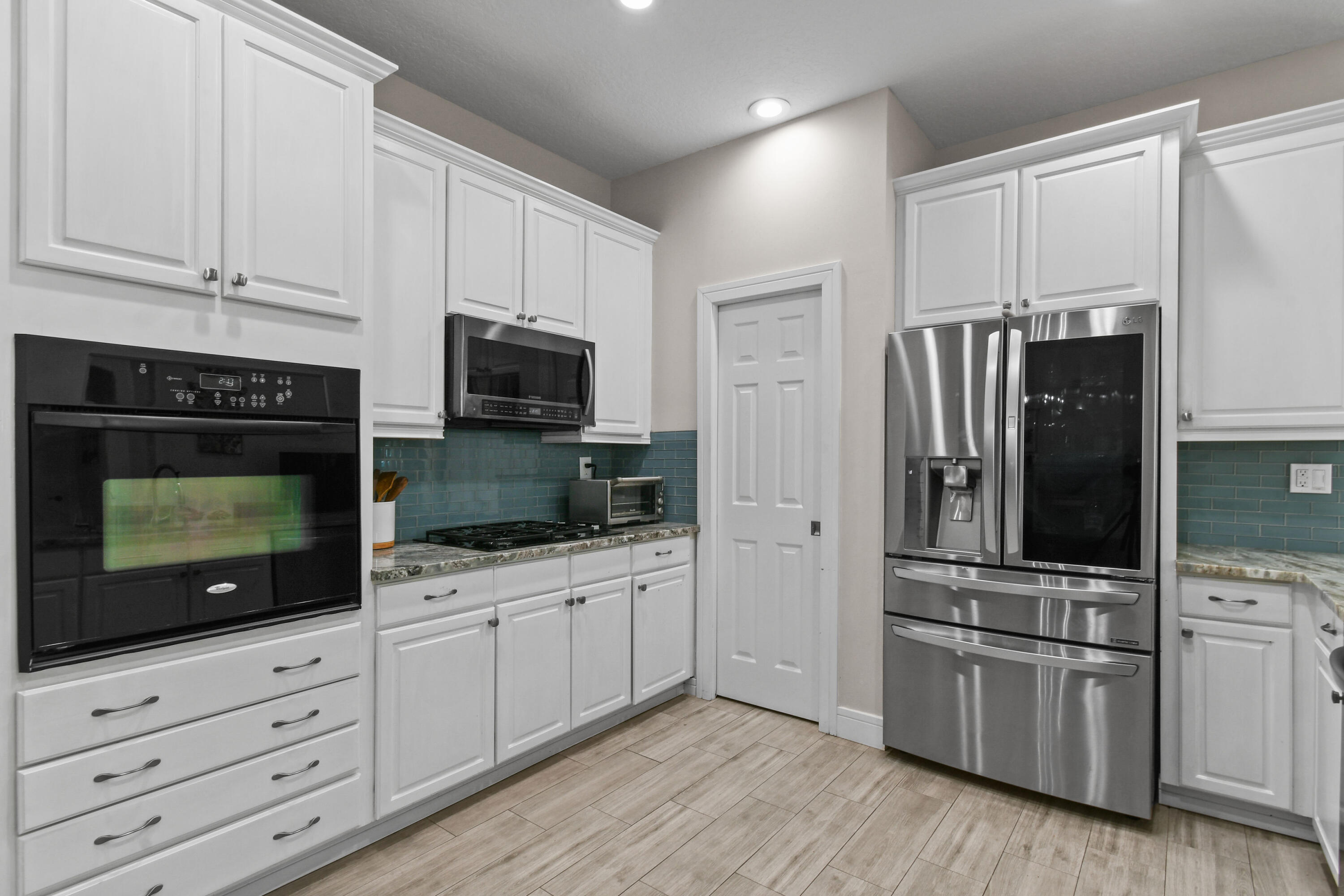 303 Hardwood Point Jupiter, FL 33458 - Photo 23 of 75 a kitchen with white cabinets and stainless steel appliances